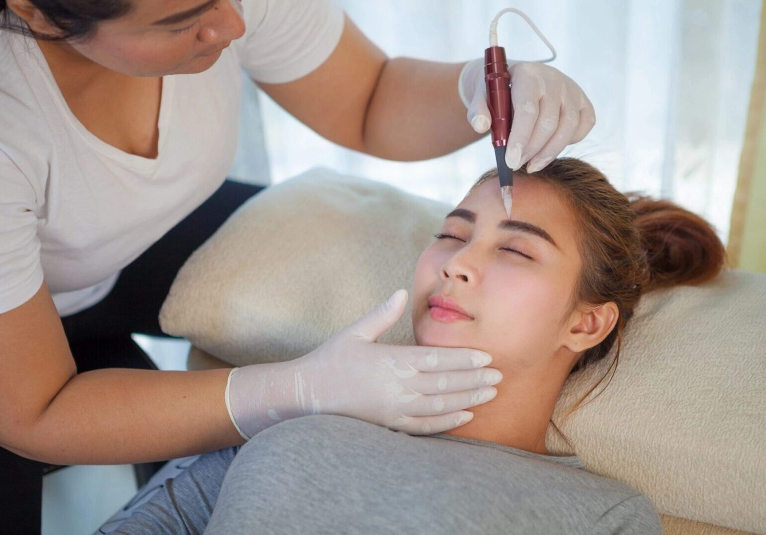 Woman receiving eyebrow microblading treatment